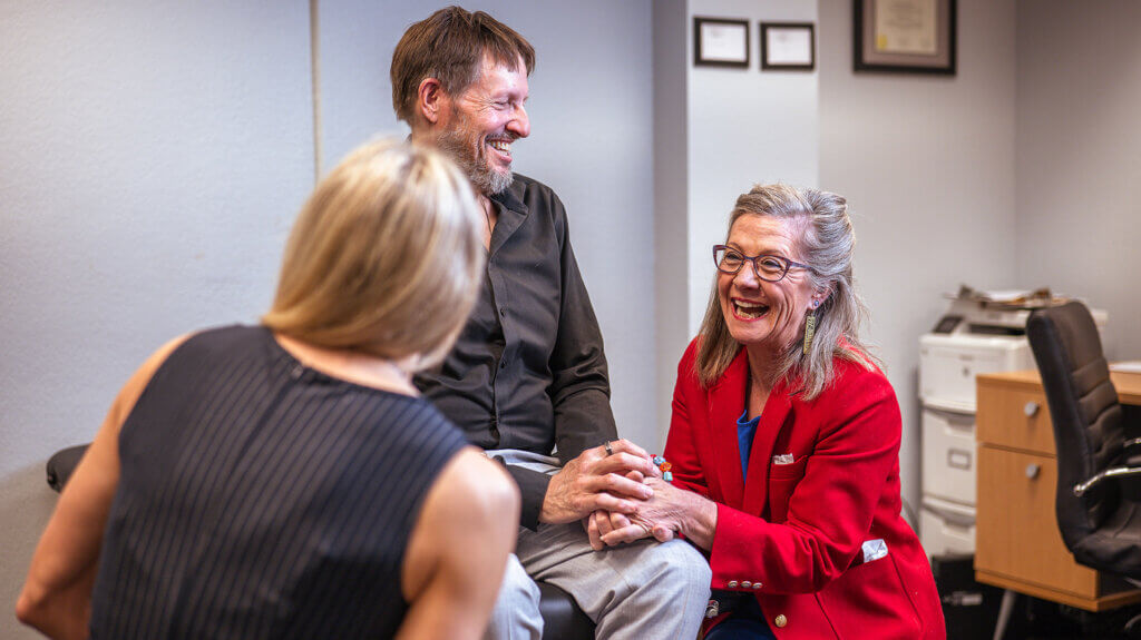 A holistic healthcare practitioner speaking with 2 patients in an exam room
