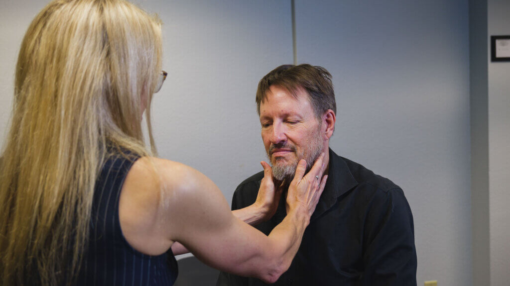 Dr. Bybee holding the neck of a patient during a holistic healthcare consultation in Tucson